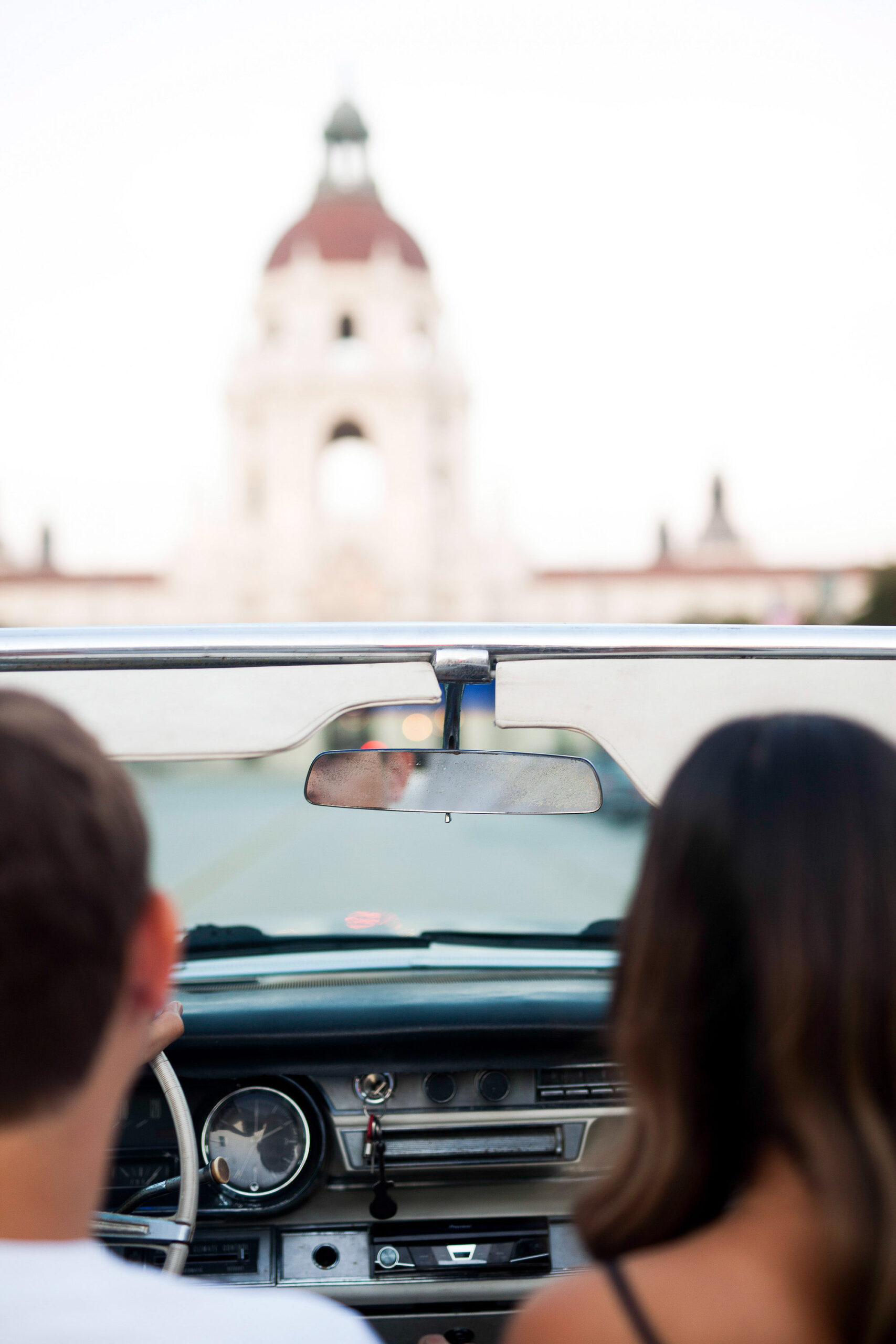 man and woman driving in a convertible car