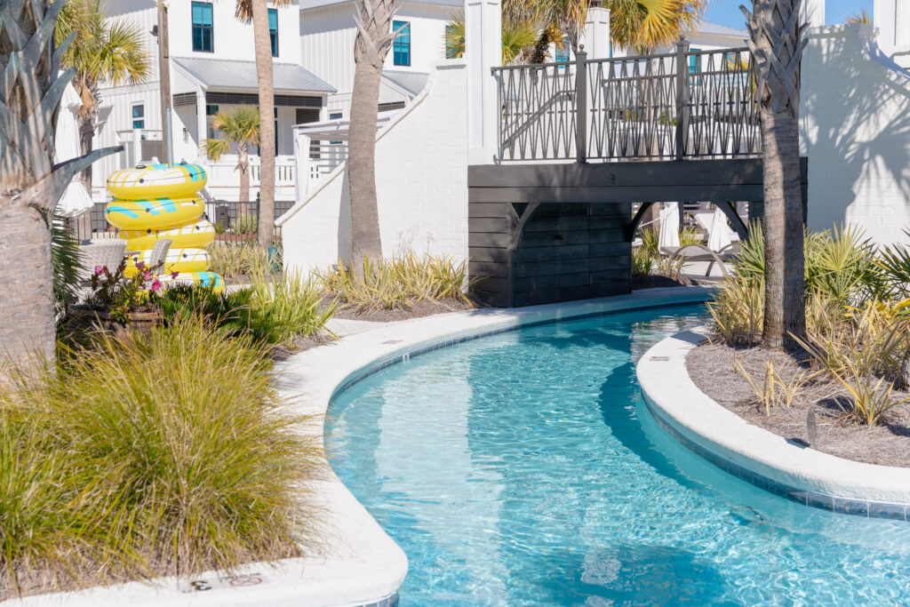 Picture of a lazy river with a bridge running over top of it with floaties near by